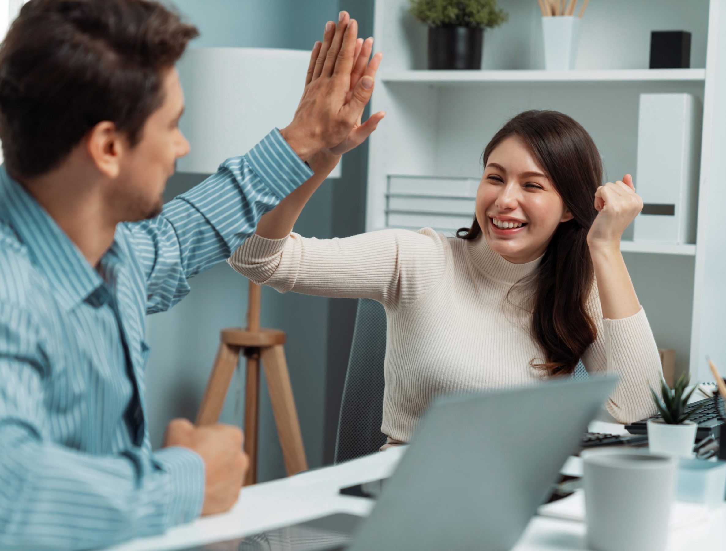 Smiling happy coworkers making hand high five also raising fist up of successful creative business project plan with highest profit value job in casual day at modern office at morning time. Postulate.