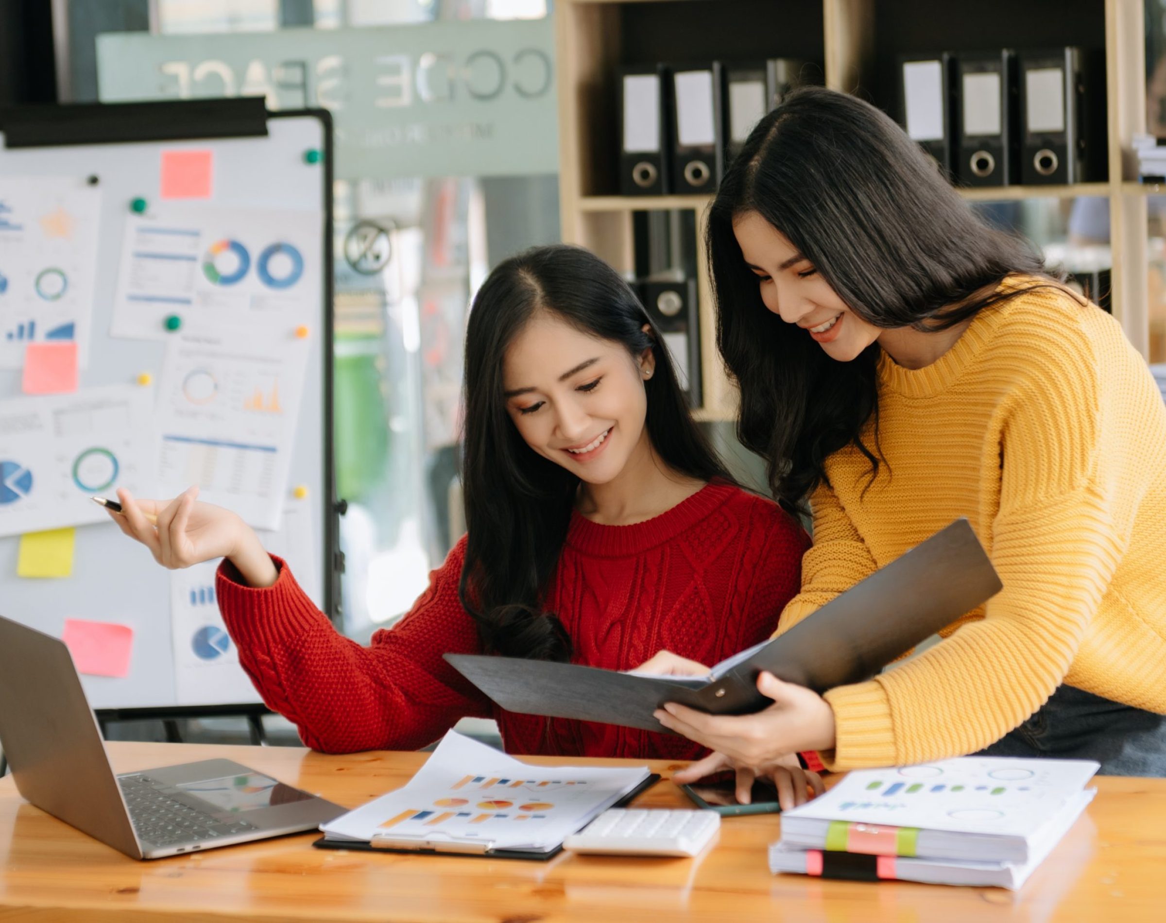 Two Asian businesswoman discuss investment project working and planning strategy with tablet laptop computer in modern office.