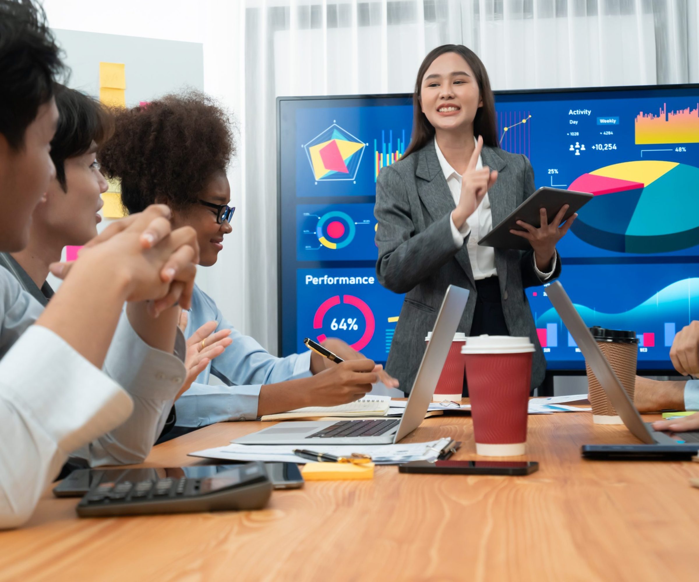 Young asian businesswoman presenting data analysis dashboard on TV screen in modern meeting. Business presentation with group of business people in conference room. Concord
